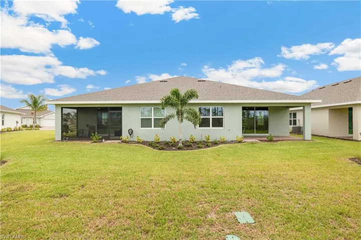 Rear view of house featuring a sunroom and a lawn
