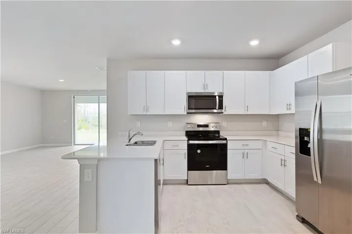 Kitchen featuring sink, white cabinets, light wood-type flooring, and stainless steel appliances