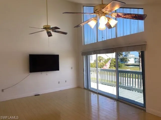 Unfurnished living room featuring a towering ceiling, ceiling fan, and hardwood / wood-style floors