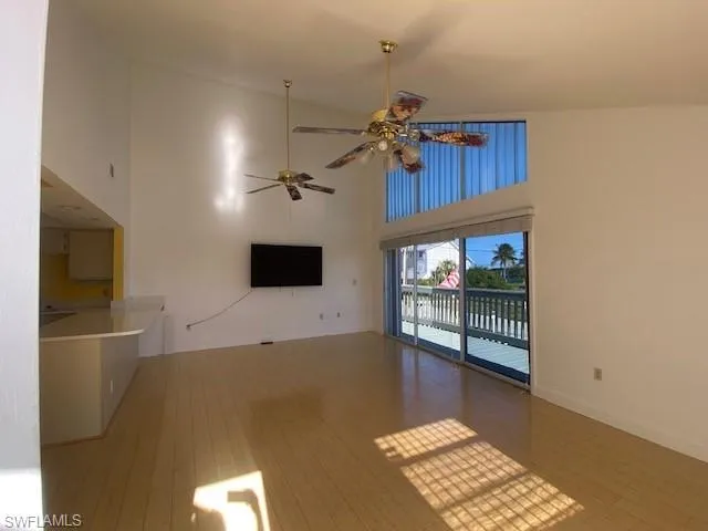 Unfurnished living room featuring a towering ceiling, wood-type flooring, and a ceiling fan