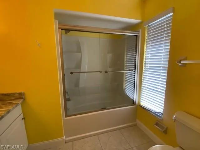 Full bathroom featuring enclosed tub / shower combo, vanity, and healthy amount of natural light