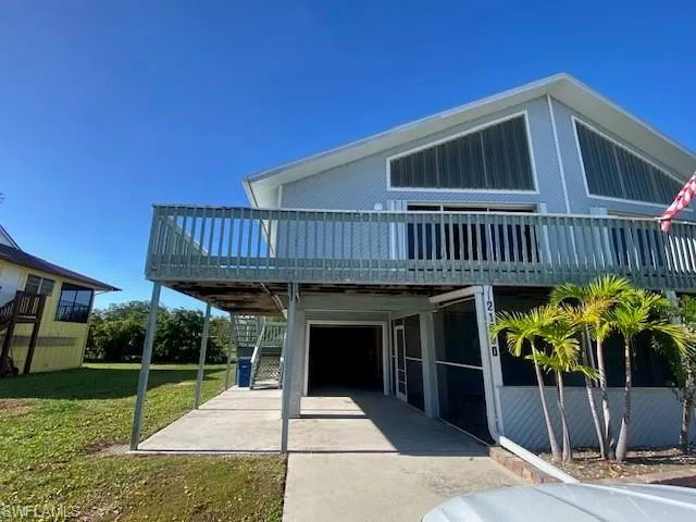 View of front of house featuring a deck, a front lawn, a patio area, and stairs