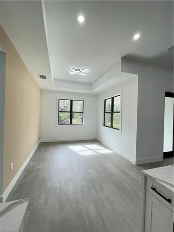 Unfurnished living room featuring light hardwood / wood-style floors and a tray ceiling