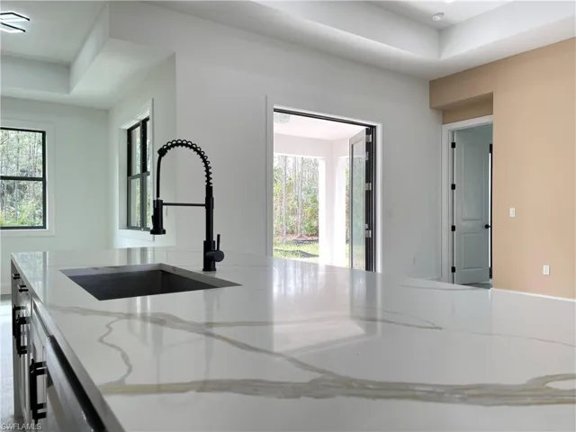 Kitchen featuring light stone counters, sink, a wealth of natural light, and dishwasher