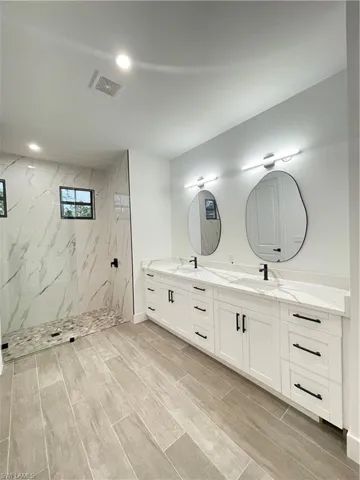Bathroom featuring tiled shower and vanity