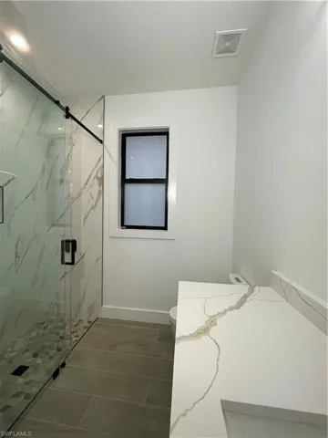 Bathroom featuring a shower with door and toilet