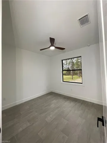 Unfurnished room with dark hardwood / wood-style flooring and ceiling fan