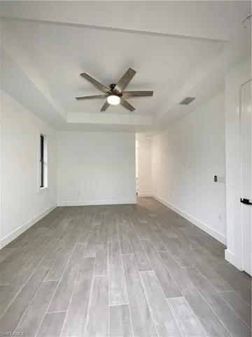 Spare room featuring a raised ceiling, hardwood / wood-style flooring, and ceiling fan