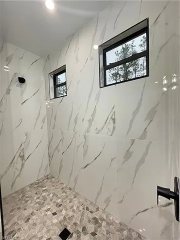 Bathroom featuring tiled shower and a wealth of natural light