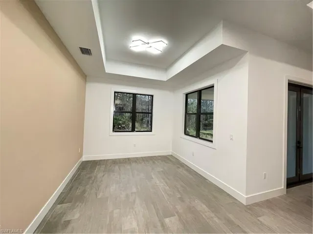 Empty room with a tray ceiling and light wood-type flooring