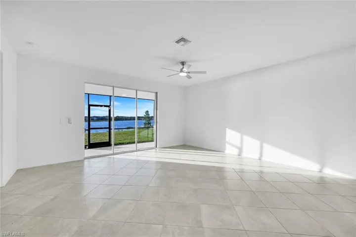 Empty room featuring a water view, ceiling fan, and light tile patterned floors