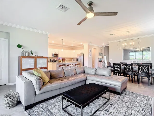 Living room with ceiling fan with notable chandelier and crown molding