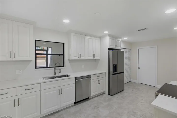 Kitchen with appliances with stainless steel finishes, white cabinets, light stone counters, and recessed lighting