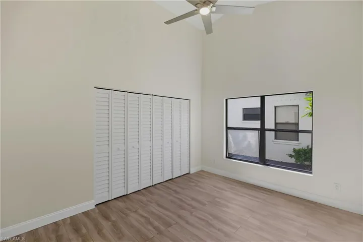 Unfurnished bedroom featuring light wood-style floors, a towering ceiling, ceiling fan, and a closet