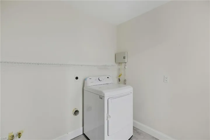 Washroom with dryer and baseboards