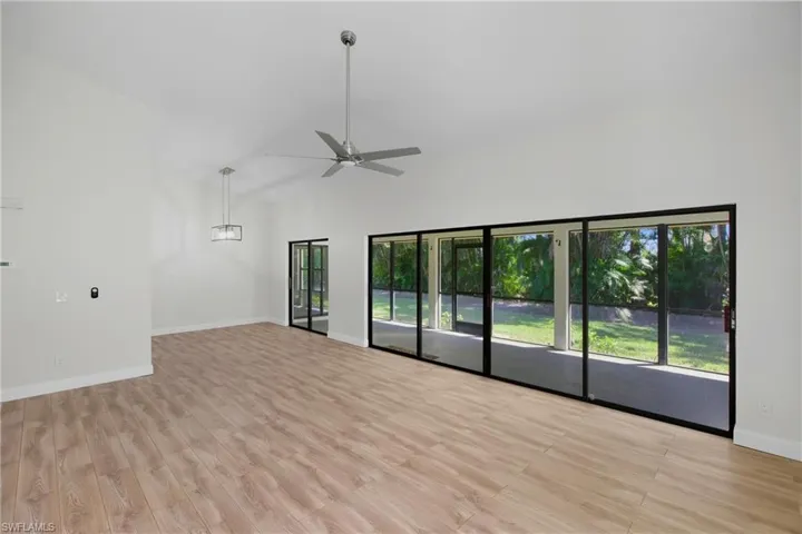 Unfurnished room with ceiling fan, light wood-type flooring, and high vaulted ceiling