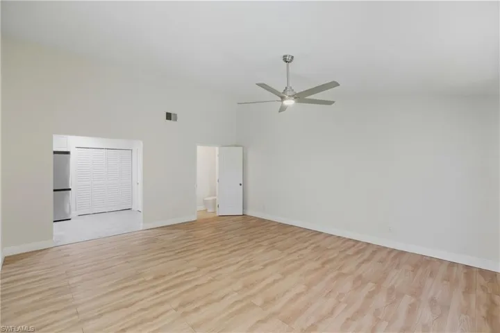 Empty room featuring light wood finished floors, a towering ceiling, and a ceiling fan