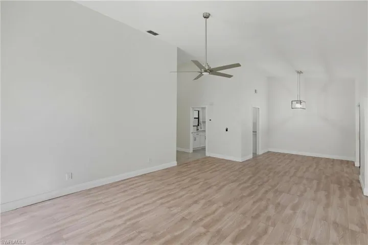 Unfurnished living room featuring high vaulted ceiling and light wood-style floors