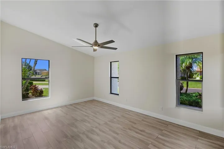 Primary bedroom with light wood-style flooring, a ceiling fan, and vaulted ceiling