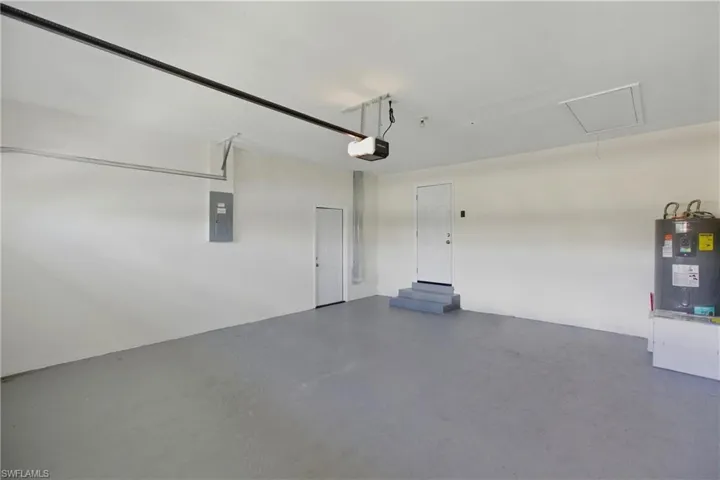 Garage featuring water heater, electric panel, and a garage door opener