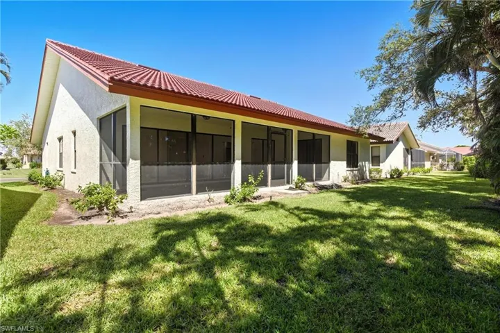 Rear view of house featuring stucco siding, a sunroom, a yard, and a tile roof