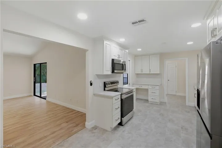 Kitchen featuring stainless steel appliances, white cabinets, recessed lighting, light wood-style floors, and open floor plan