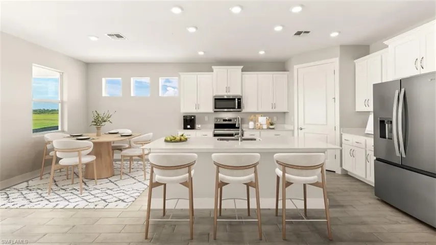 Kitchen featuring white cabinetry, stainless steel appliances, a center island with seating, recessed lighting, and wood-finish flooring