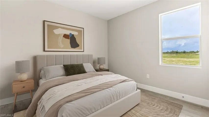Neutral tone walls with a large window, wood-finish flooring, and a plush upholstered headboard