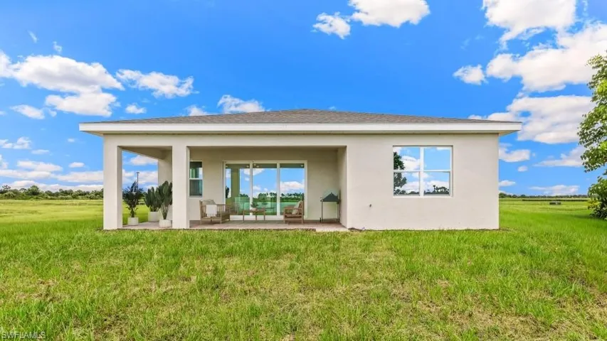 Rear exterior featuring a covered patio, sliding glass doors, and a large picture window
