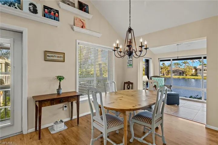 Dining area featuring wood finished floors, a water view, plenty of natural light, and high vaulted ceiling