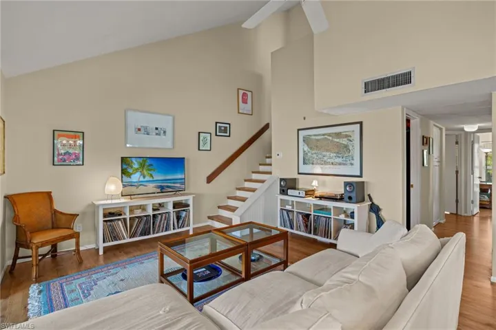 Living area featuring stairway, high vaulted ceiling, and wood finished floors