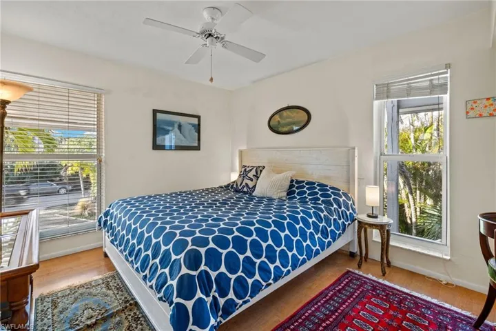 Bedroom featuring wood finished floors, a ceiling fan, and multiple windows