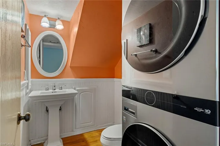 Bathroom with wainscoting, wood finished floors, and stacked washer / dryer