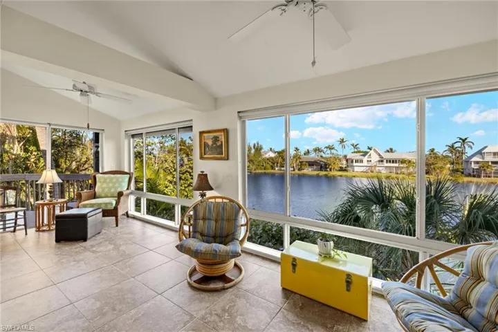 Sunroom with vaulted ceiling, a water view, and tile patterned floors