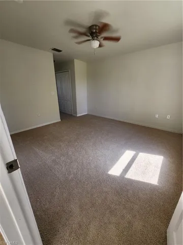 Carpeted empty room with baseboards and ceiling fan
