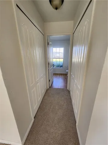 Hallway with dark carpet and baseboards