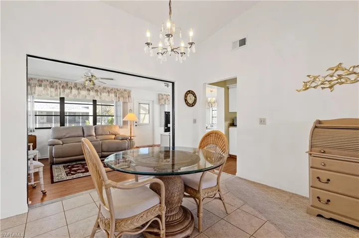 Dining space with light tile patterned floors, high vaulted ceiling, ceiling fan, and a chandelier