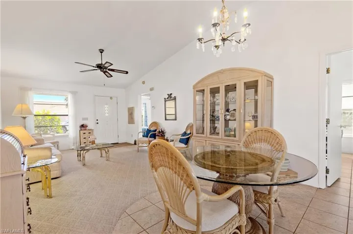 Dining area featuring high vaulted ceiling, ceiling fan, a chandelier, and carpet