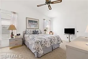 Bedroom with vaulted ceiling, ceiling fan, and light colored carpet