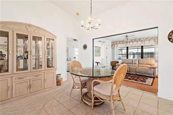 Dining space with a chandelier, light tile patterned flooring, a ceiling fan, and vaulted ceiling