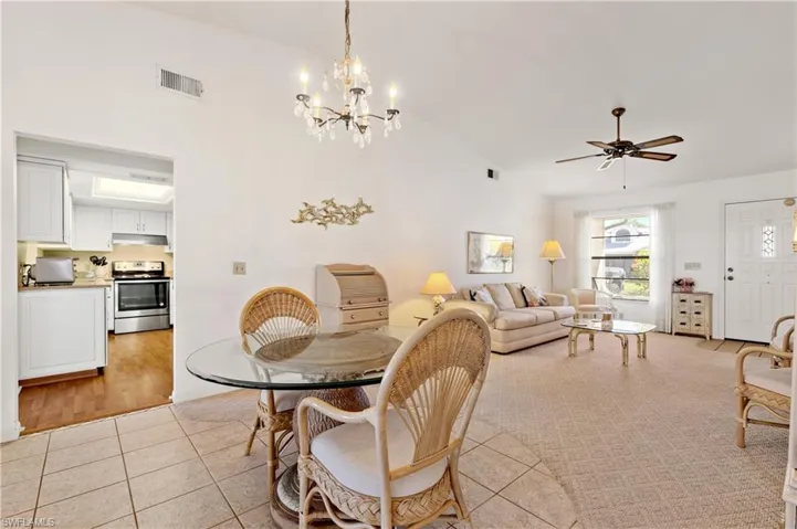 Dining space featuring light tile patterned floors, a ceiling fan, high vaulted ceiling, and a chandelier