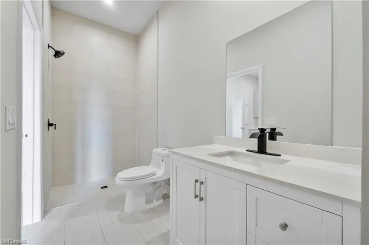 Full bath featuring vanity, a tile shower, and tile patterned floors