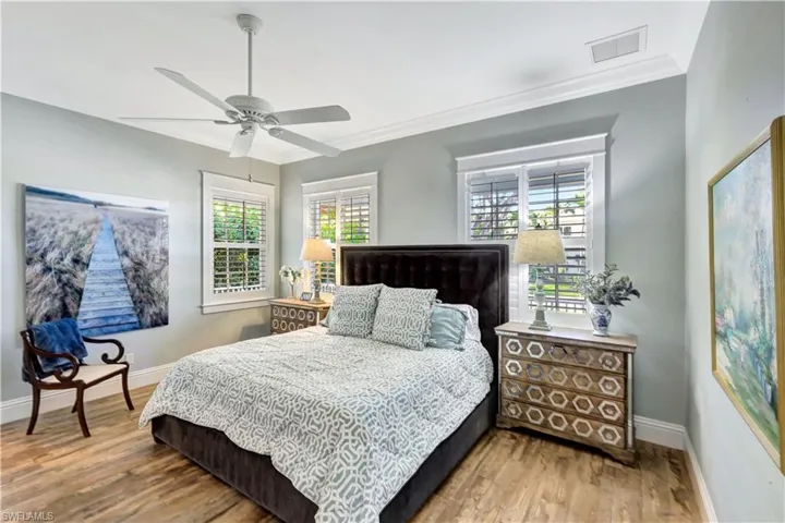 Bedroom with a ceiling fan, wood finished floors, and crown molding