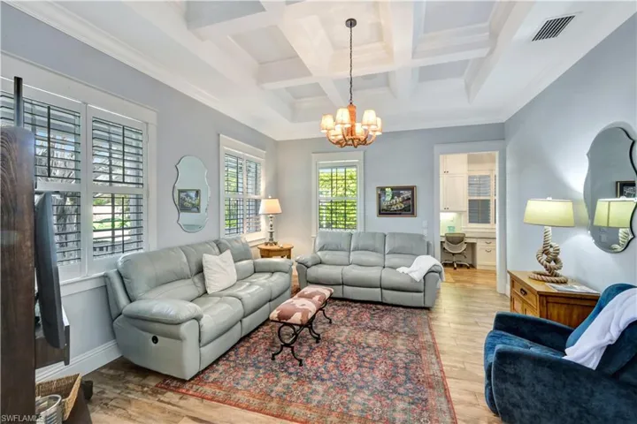 Family room with crown molding, light wood inspired tile floors, a chandelier, beam ceiling, and coffered ceiling