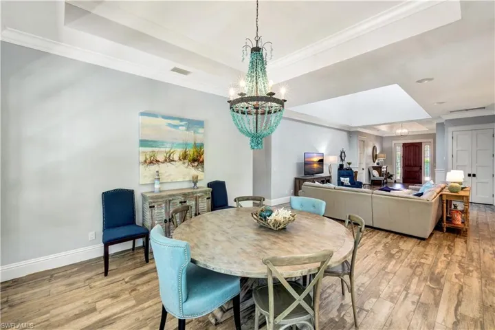 Dining area with crown molding, a tray ceiling, light wood-type flooring, and a chandelier