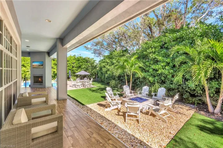 View of patio featuring a fireplace, a fire pit, and view of lush landscaping