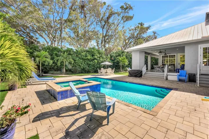 View of pool with a patio area, a pool with connected hot tub, outdoor dining space, and view of wooded area