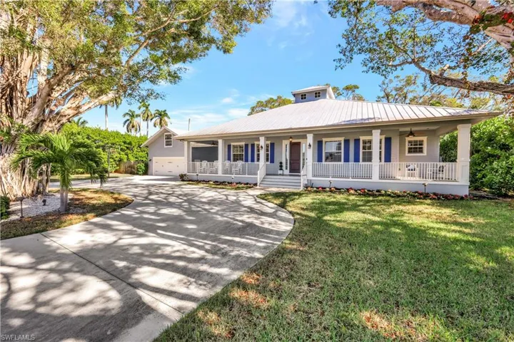 View of front facade featuring a porch, concrete driveway, a front lawn, and a metal roof