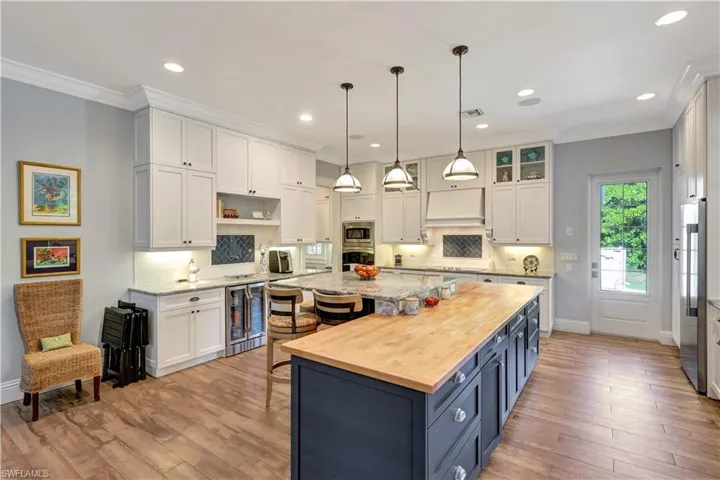 Kitchen featuring white cabinets, a kitchen breakfast bar, backsplash, blue cabinets, and ornamental molding