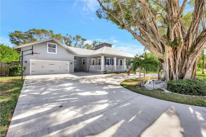 View of front of house with a metal roof, concrete driveway, and covered porch
